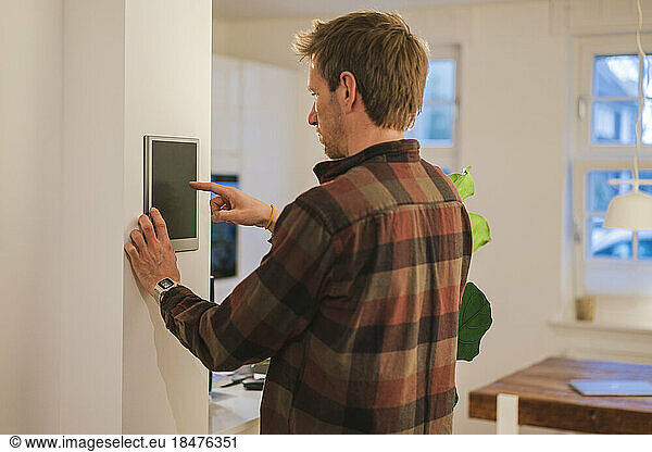 Man using smart home device on wall at home