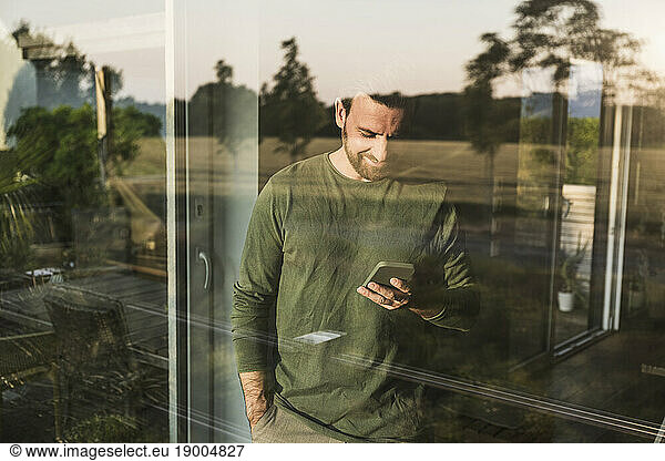 Man using smart phone seen through glass