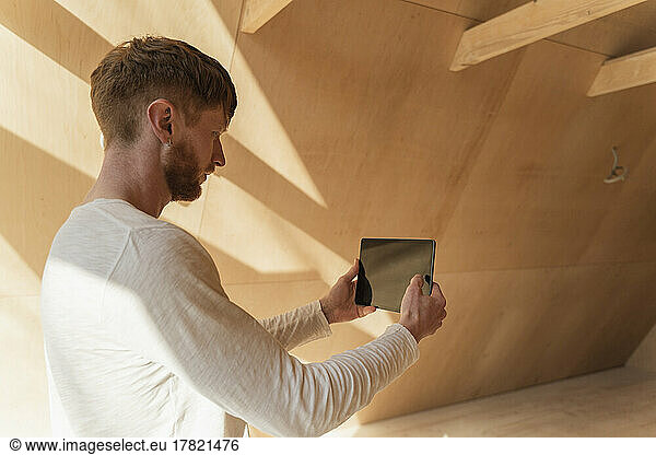 Man using tablet pc to visualise home interior at new wooden eco house
