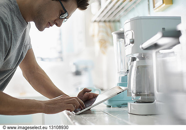 Man using tablet while standing at kitchen counter
