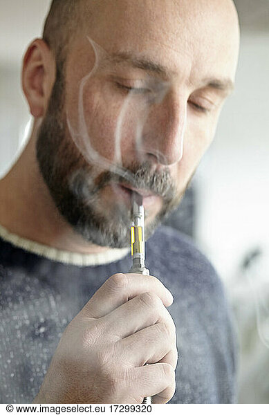 man vaping cannabis distillate with vape pen