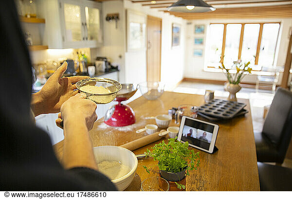 Man video chatting and making fresh pizza dough in kitchen