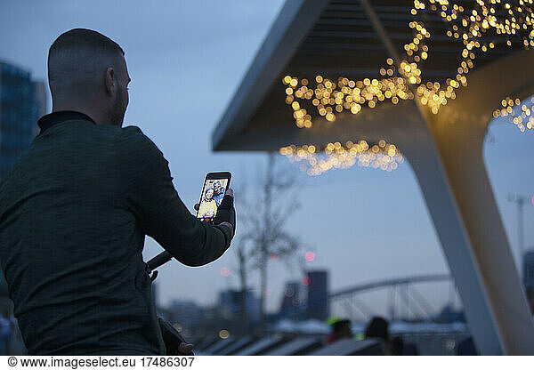 Man video chatting with family on smart phone under bridge at night