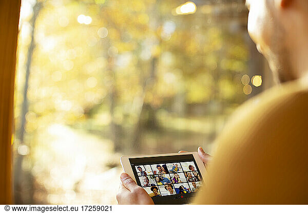 Man video chatting with friends on digital tablet at sunny window