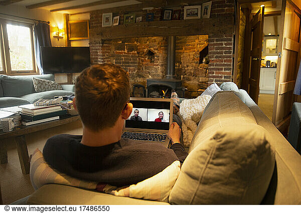 Man video conferencing with colleagues from living room sofa