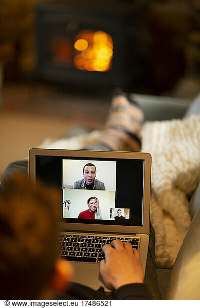 Man video conferencing with colleagues on laptop in living room