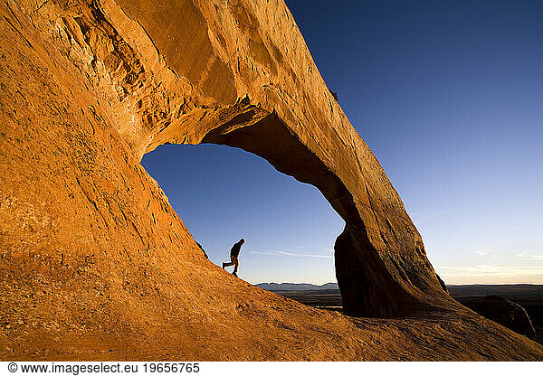 man walking below Wilson Arch near Moab  Utah