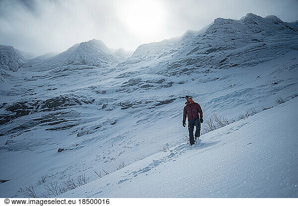 Man walking in front of dramatic snowy mountain ridge