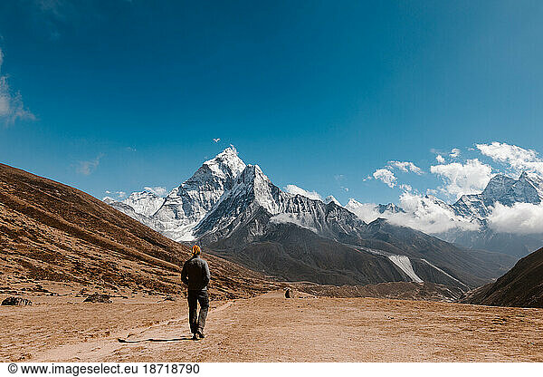 Man walking in front of high mountains