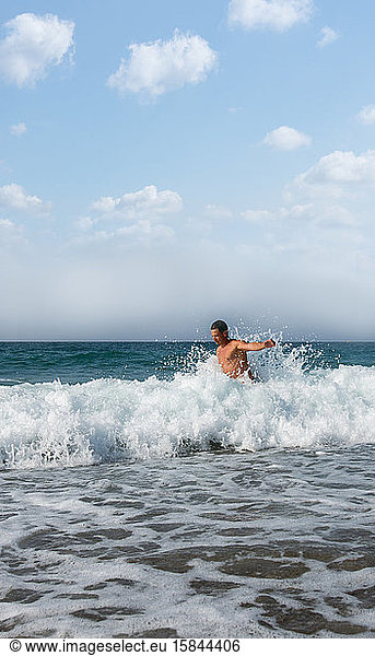 Man warms up in the strong waves of Greece in the summer