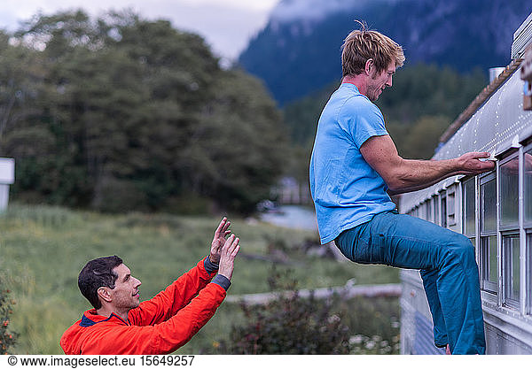Man watching back of friend climbing motorhome  Squamish  British Columbia  Canada