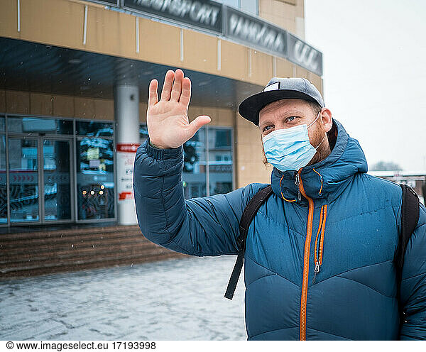 Man wearing anti virus masks waving to his friends