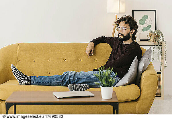 Man wearing eyeglasses sitting on sofa at home