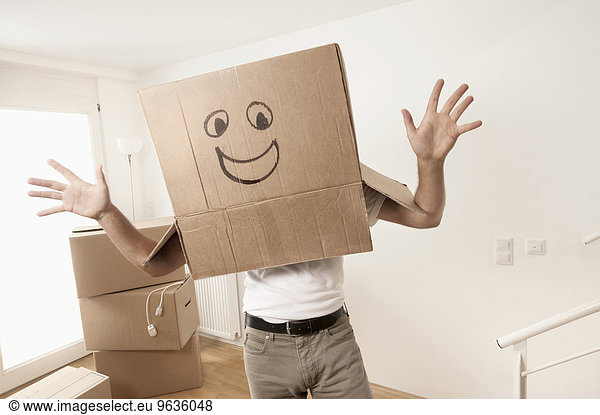 Man wearing happy face moving box over head and dancing