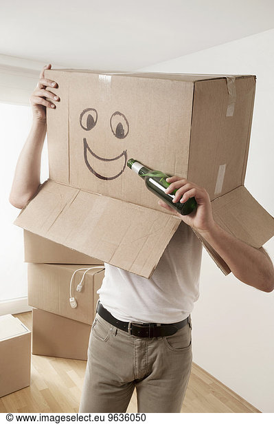 Man wearing happy face moving box over head and pretending to drink beer