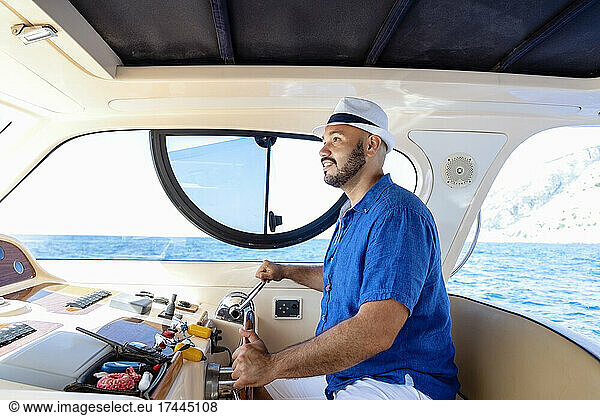 Man wearing hat driving motorboat