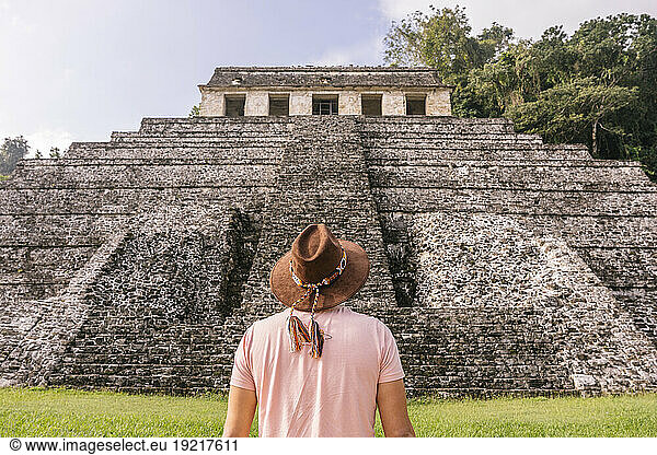 Man wearing hat standing in front of Mayan old ruins