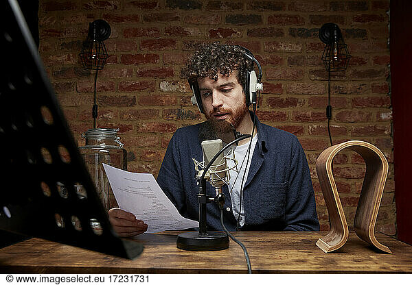 Man wearing headphones reading  speaking into microphone
