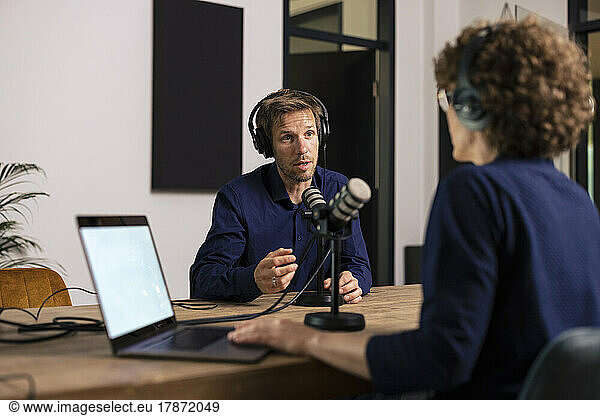 Man wearing headset talking with guest in recording studio