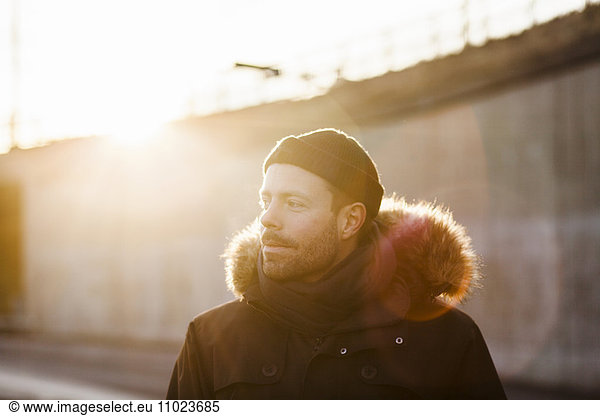 Man wearing jacket looking away on sunny day