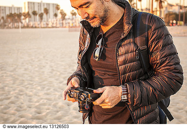 Man wearing jacket while holding camera at beach