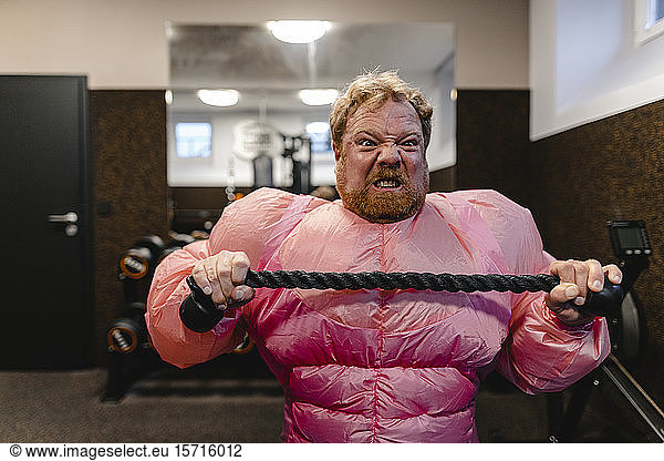 Man wearing pink bodybuilder costume practicing in gym