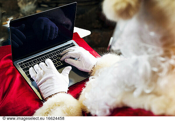 Man wearing Santa Claus costume using laptop while sitting at home
