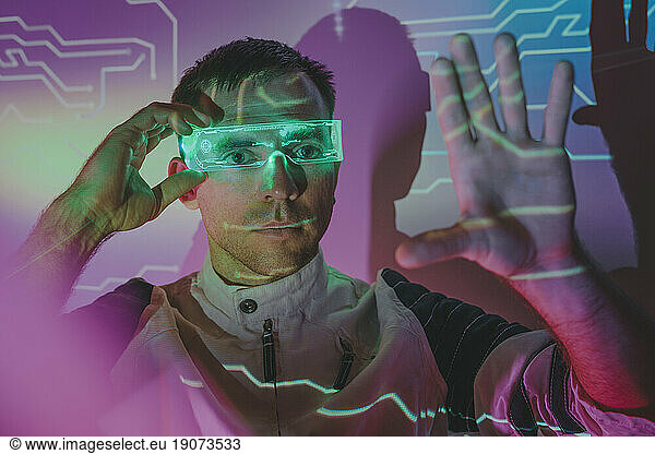 Man wearing smart glasses and gesturing in neon lights
