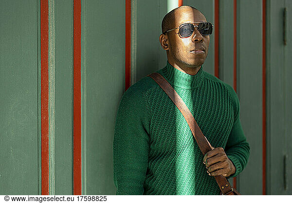 Man wearing sunglasses standing in front of wall