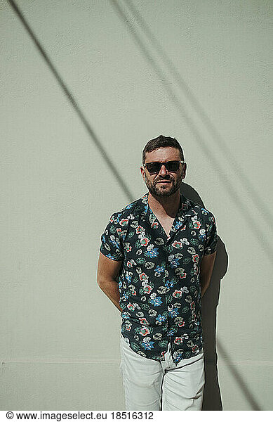 Man wearing sunglasses standing in front of wall