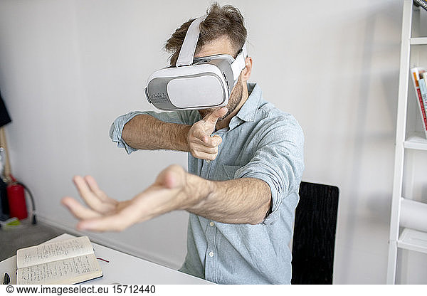 Man wearing VR glasses at desk in office