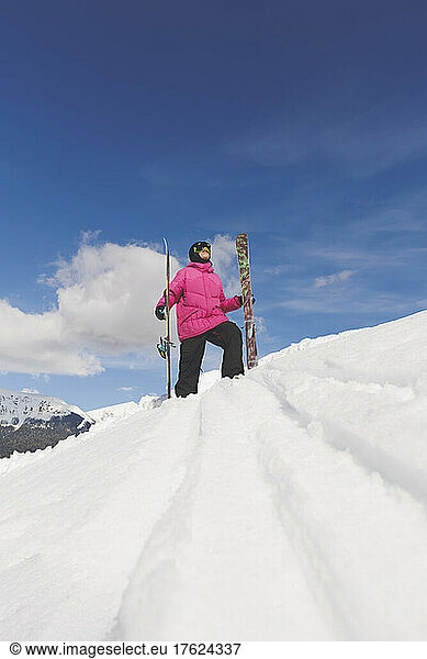 Man wearing warm clothing holding ski walking on snow