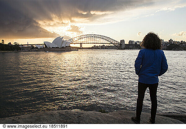 Man wearing winter jacket  staring at the Sydney Harbour during Sunset