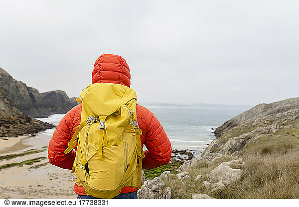 Man wearing yellow backpack looking at view