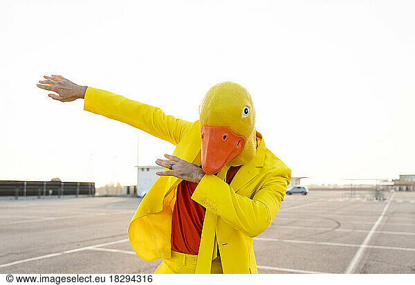 Man wearing yellow duck mask dancing in parking lot