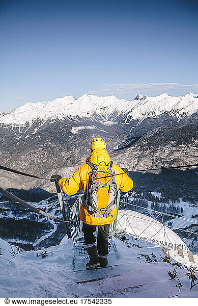 Man wearing yellow jacket hiking downhill mountains