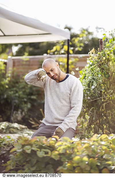 Man wiping sweat form forehead while gardening at yard