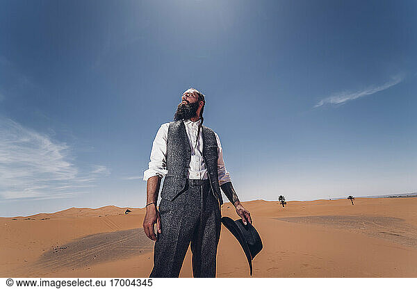 Man with a beard and hat in the dunes of the desert of Morocco