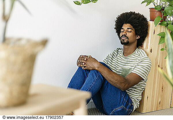 Man with Afro hairstyle leaning on cabinet at home