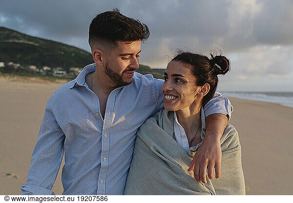 Man with arm around girlfriend at beach