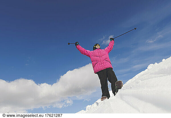 Man with arms raised holding ski poles standing on snow