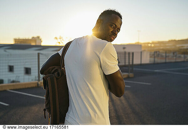 Man with backpack at parking lot during sunset