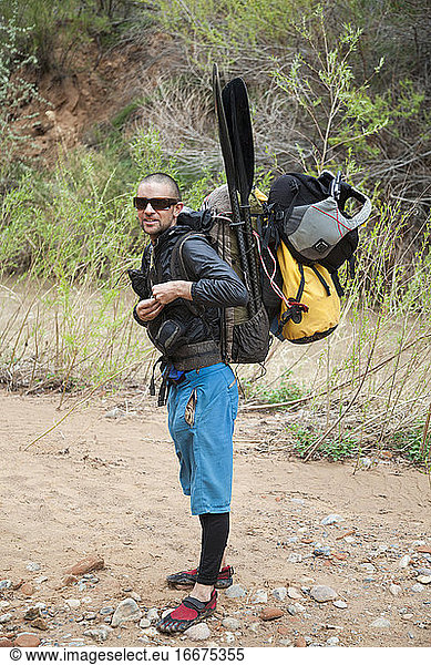Man with backpack with packrafting gear on Escalante River  Utah