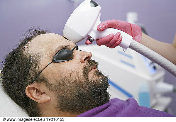 Man with beard getting laser removal treatment at clinic