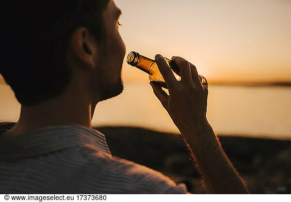 Man with beer bottle during sunset