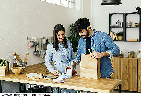 Man with box standing by woman in kitchen at home