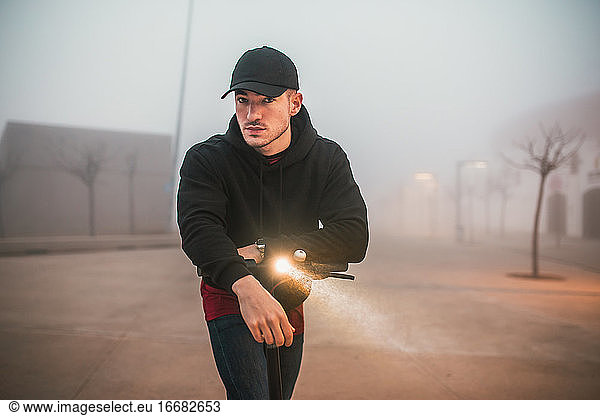 man with cap on electric scooter during a foggy day