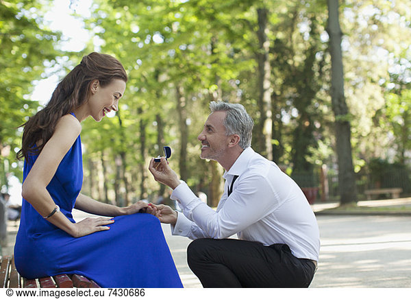 Man with engagement ring proposing to girlfriend in park