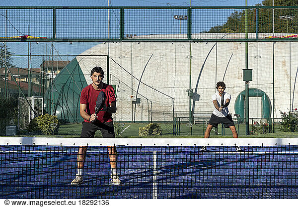 Man with friend playing paddle tennis at sports court