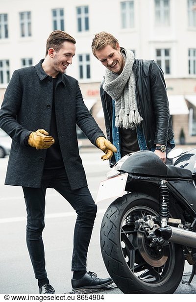 Man with friend pointing at motorcycle